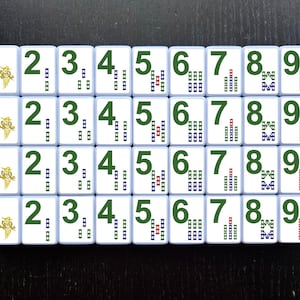 May include: A set of nine white tiles with black numbers 1 through 9. Each tile has a different pattern of green, blue, and red squares.