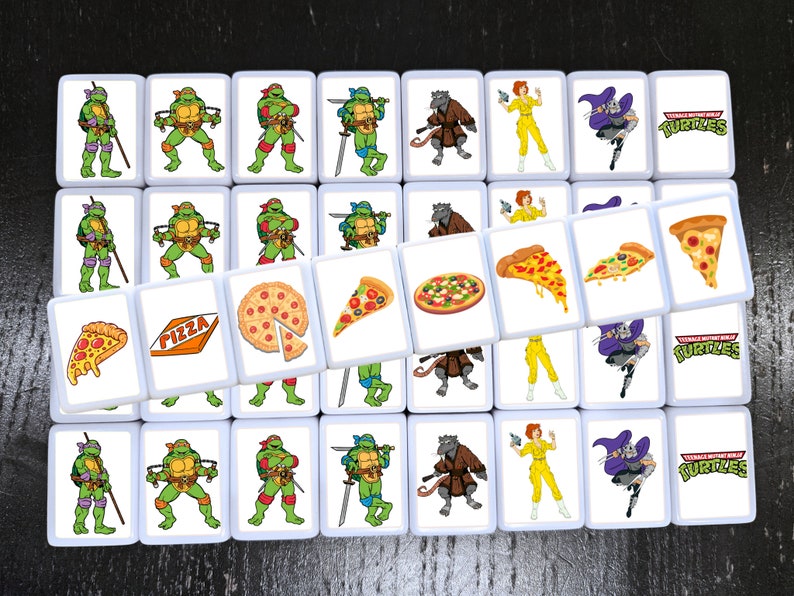 May include: A set of 25 white square tiles with images of Teenage Mutant Ninja Turtles characters, pizza slices, and pizza boxes. The tiles are arranged in a grid pattern. The tiles feature the words "Teenage Mutant Ninja Turtles" and "Pizza".