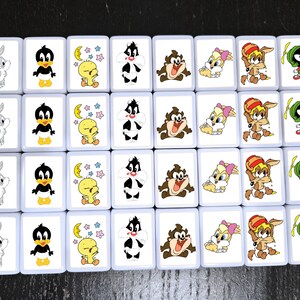 Może przedstawiać: Zestaw prostokątnych płytek z postaciami z Looney Tunes. Płytki przedstawiają obrazy Kr&oacute;lika Bugsa, Kaczora Daffy'ego, Tweety'ego, Sylwestra, Taz, Loli Bunny, Kojota i Marsjanina Marvina. Płytki mają białe tło z jasnoniebieską obw&oacute;dką.