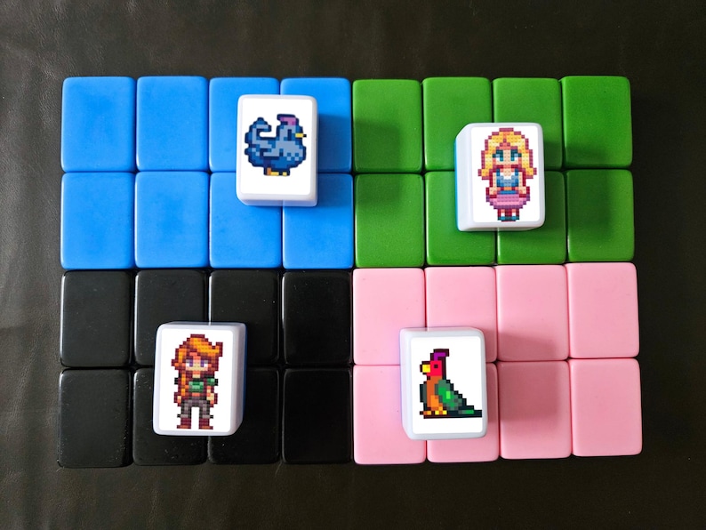 May include: A set of colorful tiles arranged in rows, featuring pixelated images of a chicken, a woman, a girl, and a parrot. The tiles are set against a black background, with blue, green, black, and pink tiles.