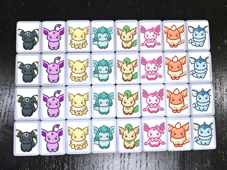 Puede incluir: Un conjunto de 24 azulejos de cer&aacute;mica blanca con im&aacute;genes de dibujos animados coloridos de varios personajes de Pok&eacute;mon. Cada azulejo presenta un Pok&eacute;mon diferente, incluyendo Eevee, Vaporeon, Jolteon, Flareon, Espeon, Umbreon, Leafeon, Glaceon, Sylveon, y otros.