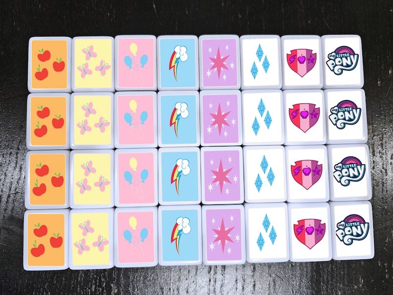 May include: A set of 16 colourful square tiles with various images, including apples, butterflies, balloons, a rainbow, a star, diamonds, a heart with a shield, and the words "My Little Pony".