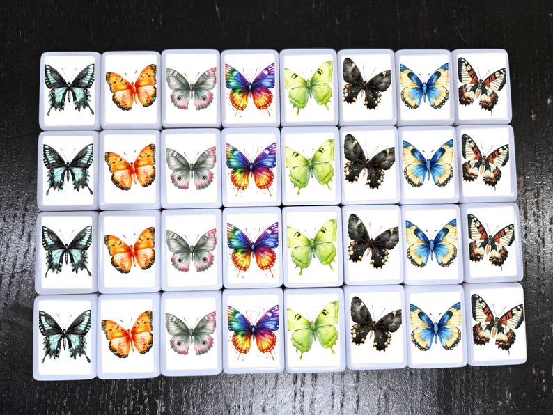 May include: A collection of 30 square tiles, each featuring a watercolor butterfly design. The butterflies vary in color, including blue, orange, green, black, and multi-colored wings. The tiles are arranged on a dark surface.