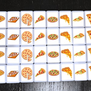 May include: A set of 36 white square tiles with images of pizza slices and whole pizzas. Each tile has the word "PIZZA" printed on it in orange letters.