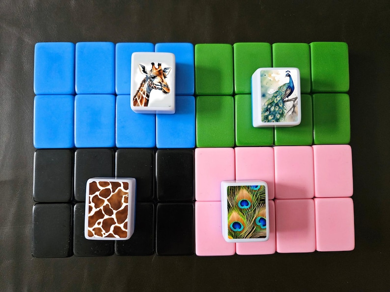 May include: Four sets of blue, green, black, and pink tiles with images of a giraffe, a peacock, a giraffe print, and a peacock feather print.