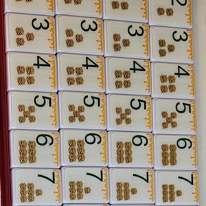 May include: A set of tiles with numbers 1-9, each tile displaying a number and a corresponding number of waffle illustrations. The tiles are arranged in a red box, suitable for a game.