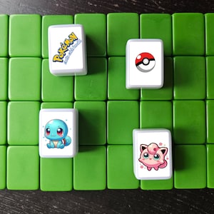 May include: Four white tiles with different Pokemon characters on a green background. The tiles feature Squirtle, a Pokeball, Jigglypuff, and the Pokemon logo with the text "Gotta Catch 'Em All!"