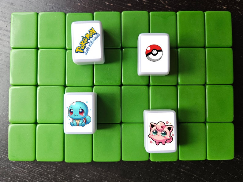 May include: Four white tiles with different Pokemon characters on a green background. The tiles feature Squirtle, a Pokeball, Jigglypuff, and the Pokemon logo with the text "Gotta Catch 'Em All!"