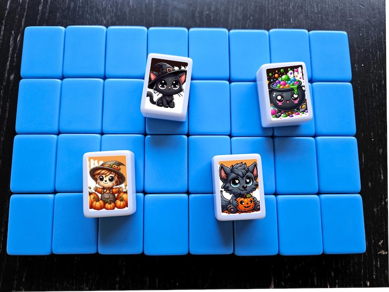 May include: A blue game board with four white tiles. Each tile features a different Halloween-themed illustration: a black cat, a cauldron with candy, a scarecrow, and a wolf.