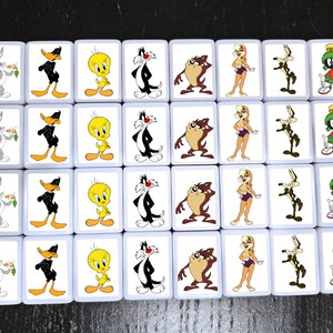 Może przedstawiać: Zestaw prostokątnych płytek z postaciami Looney Tunes. Płytki przedstawiają Kr&oacute;lika Bugsa, Kaczora Duffy'ego, Tweety'ego, Sylwestra Kota, Taz, Lolę Bunny, Wile'a E. Coyote i Marvina the Martian. Płytki mają białe tło i jasnoniebieską obw&oacute;dkę.