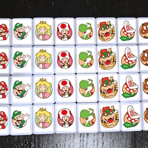 May include: A set of 20 white square tiles with colorful images of Mario, Luigi, Peach, Toad, Yoshi, Bowser, and Goomba characters from the Super Mario Bros. video game franchise.