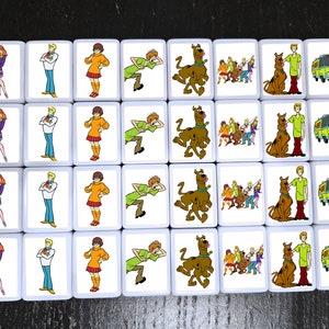 May include: A set of 20 square tiles featuring characters from the Scooby-Doo cartoon. Each tile has a different image, including Scooby-Doo, Shaggy, Velma, Daphne, and Fred. The tiles are white with a black border and are perfect for playing a game or decorating a room.