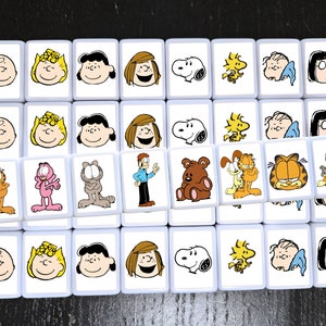 May include: A set of 36 white square tiles with cartoon images of characters from Peanuts, Garfield, and Snoopy. Each tile features a different character, including Charlie Brown, Lucy, Linus, Snoopy, Garfield, Odie, and Nermal.