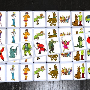 May include: A set of 24 square tiles featuring characters from the cartoon Scooby-Doo. Each tile has a different image, including Scooby-Doo, Shaggy, Velma, Daphne, Fred, and various monsters and villains. The tiles are white with a black border.