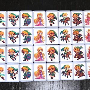 May include: A set of 24 white square tiles with images of characters from the Legend of Zelda video game series. The tiles feature Link, Zelda, and other characters in various poses and settings.