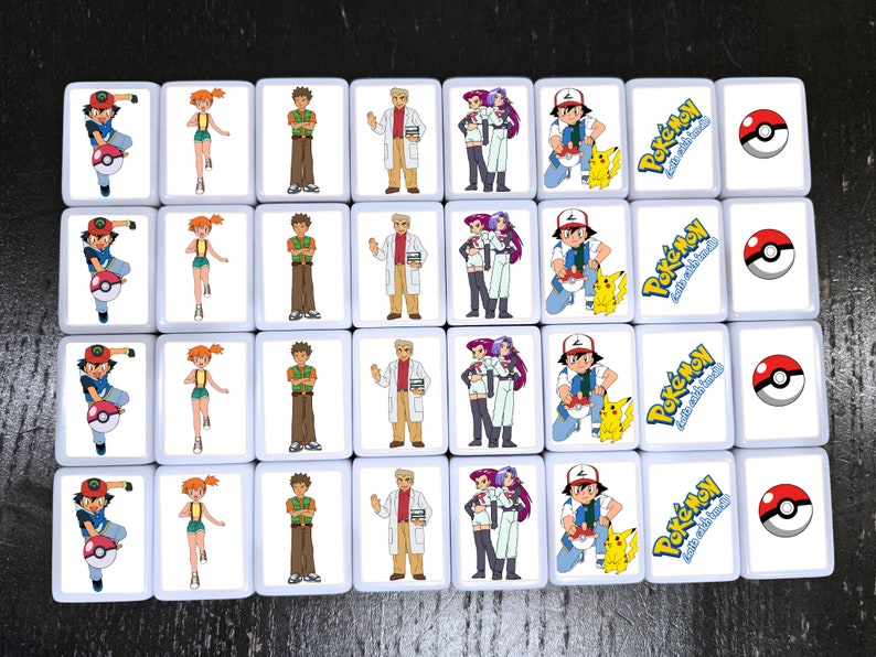 May include: A set of 16 white square tiles with images of Pokemon characters. Each tile features a different character, including Ash, Misty, Brock, and Team Rocket. The tiles also feature the Pokemon logo and the text "Gotta Catch 'Em All!"