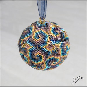 Może przedstawiać: Bombka choinkowa wykonana z koralików z geometrycznym wzorem w kolorze niebieskim, fioletowym i złotym.