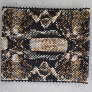 May include: A close-up of a beaded bracelet with a geometric pattern in black, brown, and beige.