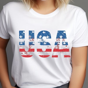 May include: White t-shirt with a distressed American flag design spelling out "USA".