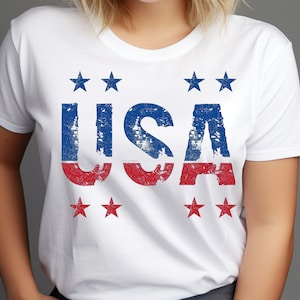 May include: White t-shirt with a distressed red, white, and blue "USA" graphic. The graphic is surrounded by six red stars.