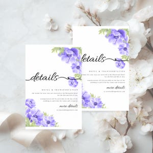 May include: Two white wedding details cards with purple floral accents. The cards feature the word "details" in elegant script and include information about hotel and transportation for the event. The cards are surrounded by white flowers.