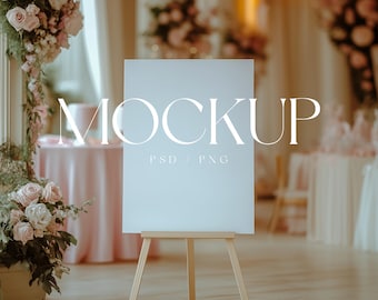 May include: A white sign with the word "MOCKUP" in large, bold letters and the text "PSD / PNG" in smaller letters below. The sign is on a wooden easel and is in front of a blurred background of a wedding reception.
