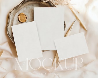 May include: A mockup scene featuring blank white cards arranged on a vintage silver tray with a gold wax seal. The cards are of varying sizes, and the scene is styled with dried flowers and a pen, all set against a cream-colored fabric. The word "MOCKUP" is displayed.