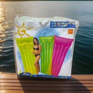 May include: An inflatable pool float package with three colorful floats: yellow-green, green, and pink. The package shows a woman in a swimsuit and the floats are approximately 72" x 30" (183 cm x 76 cm). The package is on a wooden dock with a lake in the background.