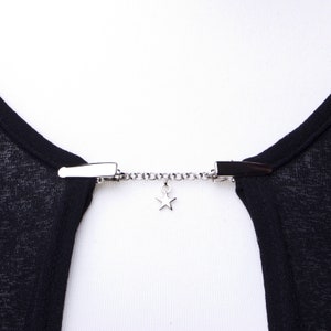 May include: A silver chain with two clips and a star charm. The chain is used to hold a garment together.