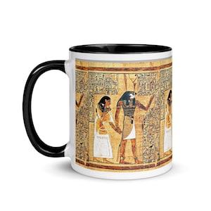 Puede incluir: Taza de cerámica blanca con borde y asa negros. La taza presenta una imagen colorida de jeroglíficos y figuras del antiguo Egipto.