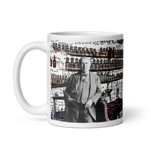 May include: White ceramic mug featuring a black and white image of a man in a suit standing in a laboratory setting. The background includes shelves of bottles and scientific equations.