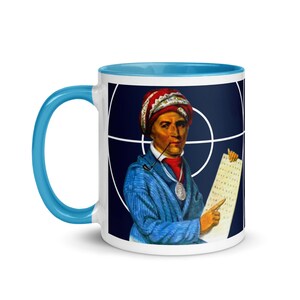May include: White ceramic coffee mug with a blue rim. The mug features a colorful illustration of a man wearing a red and white hat, a blue jacket, and a necklace. He is holding a piece of paper with text on it. The background is a blue circle with a white target.
