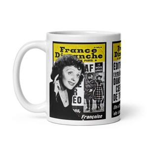 May include: White ceramic mug featuring a vintage poster design. The poster has a yellow background with black text and a black and white image of a woman. The text includes "France Dimanche" and "Paris".