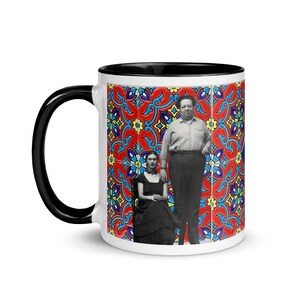 May include: White ceramic mug with a black rim and handle. The mug features a colorful tile pattern with a black and white image of Frida Kahlo and Diego Rivera.
