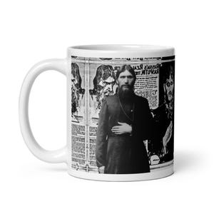May include: White ceramic mug featuring a black and white image of Grigori Rasputin. The mug's design includes newspaper clippings and portraits of Rasputin. The mug has a standard handle and a glossy finish.