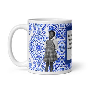 Könnte beinhalten: Weiße Keramiktasse mit blau-weißem Blumenmuster. Die Tasse zeigt ein Schwarz-Weiß-Bild eines jungen Mädchens in einem Kleid. Der Text auf der Tasse lautet "Rassismus stört sollte unsere Kinder."