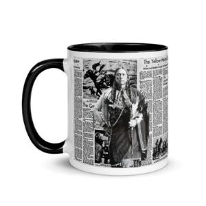 May include: A white ceramic coffee mug with a black interior and handle. The mug features a newspaper-style design with a portrait of a Native American man and text. The mug is a standard 11 oz size.