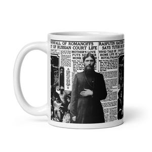 May include: White ceramic mug featuring a black and white image of a historical figure and newspaper headlines. The headlines include phrases like "Fall of Romanoffs" and "Mother's Love". The mug has a large handle.