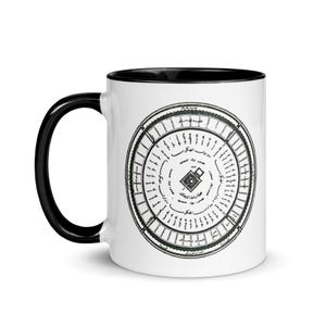 May include: White ceramic mug with a black rim and handle. The mug features a black and white illustration of a circular design with Arabic script and a small square in the center.