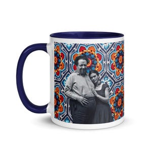 May include: White ceramic coffee mug with a blue rim. The mug features a colorful crocheted pattern with a black and white photo of a couple in the center.