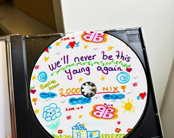 May include: A white CD with colorful drawings on it. The text on the CD says "We'll never be this young again 2000 MIX".
