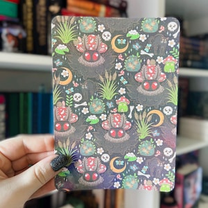 May include: A black and white patterned card with a repeating design of mushrooms, frogs, and other woodland creatures. The background is a dark gray with a subtle glitter effect.