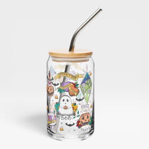 May include: A clear glass tumbler with a bamboo lid and a metal straw featuring a colorful Halloween-themed print. The design includes a ghost, jack-o'-lanterns, candy corn, and banners with the text SPOOKY SZN, SPOOKY VIBES, BOO, and TRICK OR TREAT.