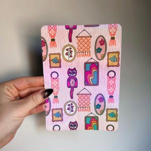 Peut inclure: Un autocollant rectangulaire rose et blanc avec un motif répété d'art encadré, de macramé et de motifs d'horloges de chat. L'art comprend des oiseaux, des fleurs et des formes abstraites. L'autocollant est tenu par une main.