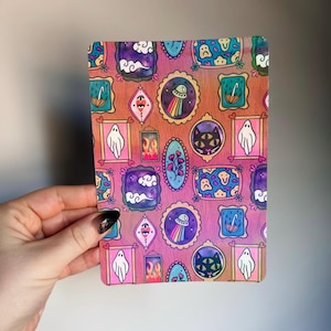 Peut inclure: Une carte rectangulaire avec un motif répété d'illustrations encadrées. Les illustrations comprennent un fantôme, un chat, un extraterrestre, des nuages et un parapluie. Les cadres sont de formes et de couleurs variées, sur un fond dégradé rose et orange.