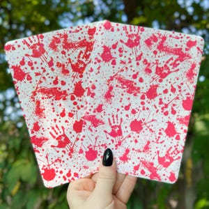 May include: Two white cards with a red splatter pattern. The splatter pattern includes handprints and blood droplets.
