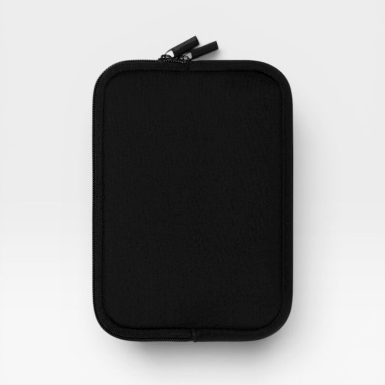 Puede incluir: Un estuche rectangular negro con cremallera y esquinas redondeadas. El exterior presenta una textura de tela negra s&oacute;lida con un cierre de cremallera negro a juego en la parte superior, que incluye dos peque&ntilde;os tiradores negros.