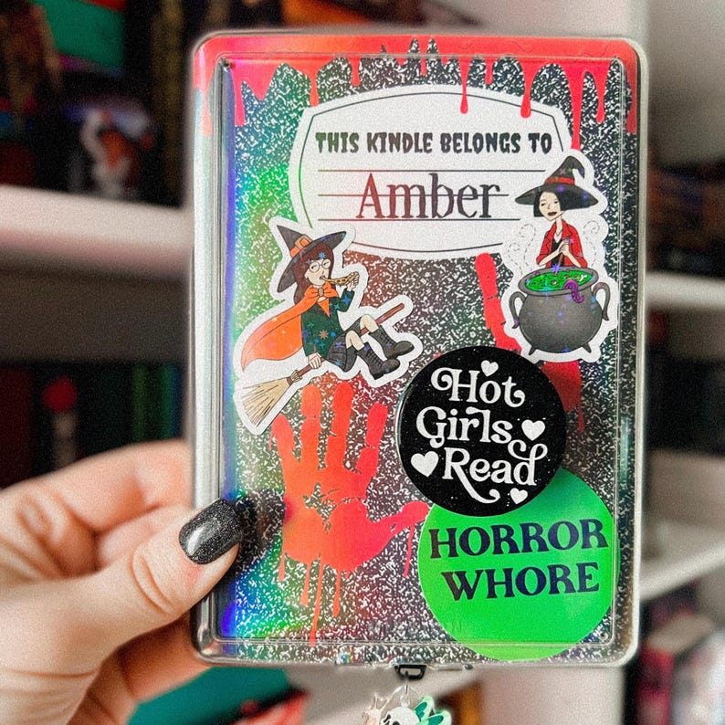 以下が含まれることがあります： 黒と銀のグリッターで覆われたKindleケース。魔女のステッカー、大釜のステッカー、「Hot Girls Read」と書かれたステッカー、「Horror Whore」と書かれたステッカーが付いています。ケースには、「This Kindle Belongs to Amber」と書かれたネームタグも付いています。