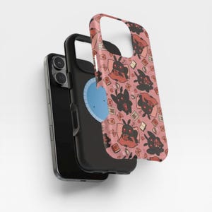May include: A black smartphone with a protective case featuring a repeating pattern of black moth-like creatures with red eyes reading books on a dusty pink background. The case displays various small icons including open books, envelopes, and coffee cups.