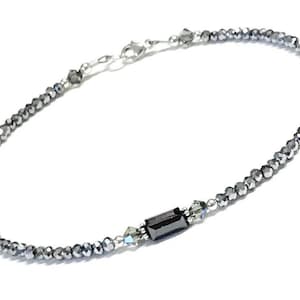 May include: A silver bracelet with black and clear crystal beads. The bracelet has a silver clasp.